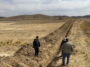 Three men standing along side a trench for a water piping system