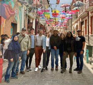 A group photo of the EWB North Texas travel team on a street with umbrellas overhead in La Paz, Bolivia