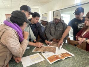 A group of individuals engaged in conversation looking at a map on a table