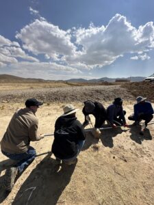 A photo of five men holding down a water pipe on the ground