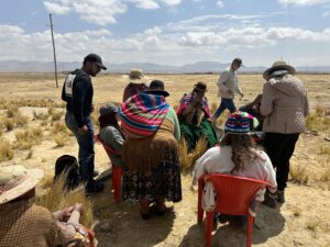 Group of individuals in a meeting outside with the women of Culli Alto, Bolivia