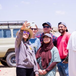 A group of individuals smiling taking a selfie on a mobile phone